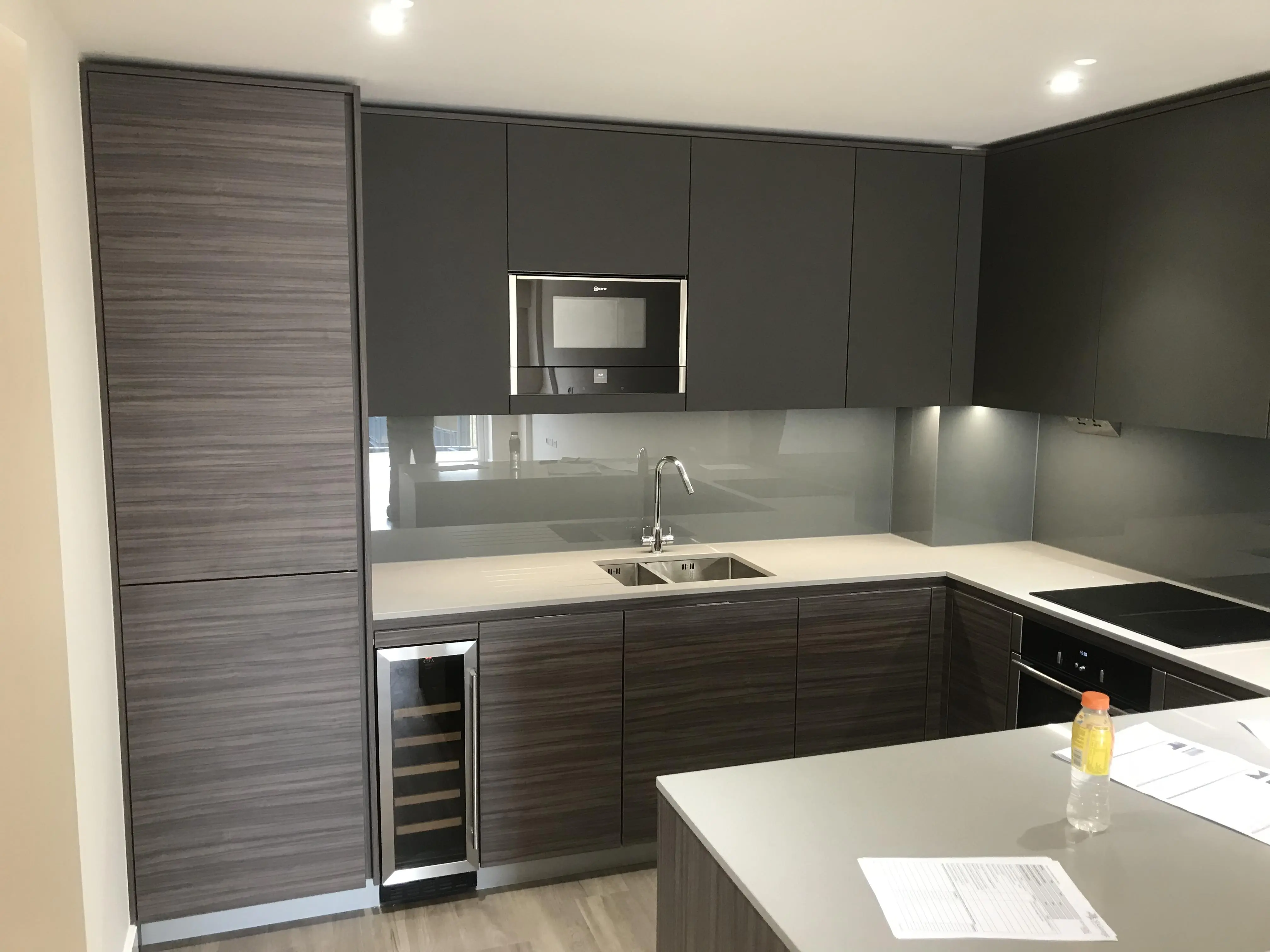 Társasházi lakás “fiatalos” konyhája. Beépített hűtő, borhűtő, mikrohullámú sütő LED-es megvilágítás, festett üveg faltakarás és kő munkalap gondoskodik a kényelemről, a funkcióról és a megjelenésről…